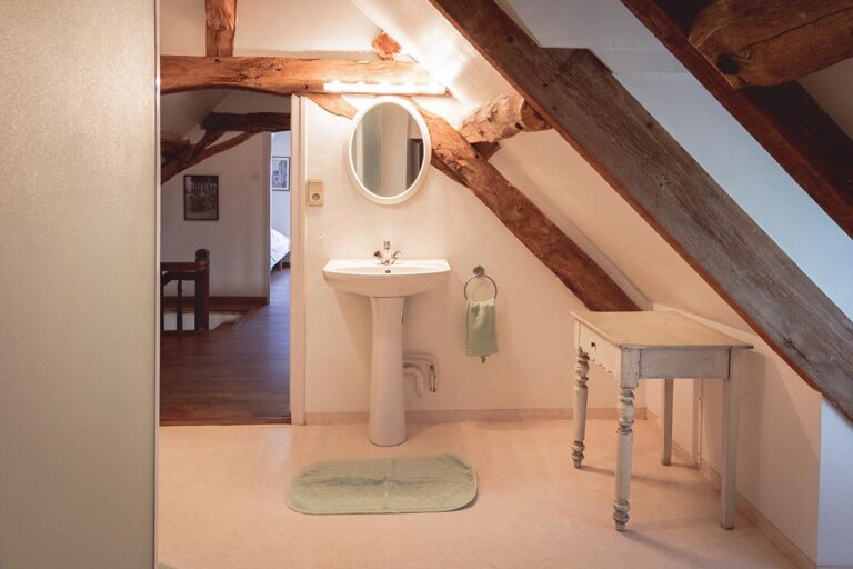 attic bathroom with sink and mirror and table