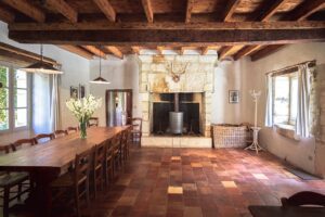 dining room with a large wooden table and 12 chairs and a large chimney. La salle à manger