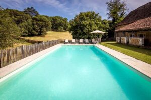 La leotardie's swimming pool with umbrella, deckchairs and view to the garden