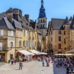 sarlat main square with houses and people sitting in cafés